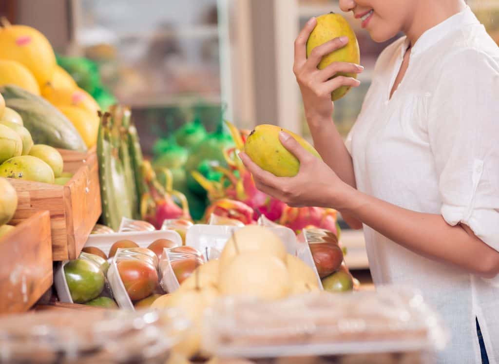 woman smelling fruit at a local market