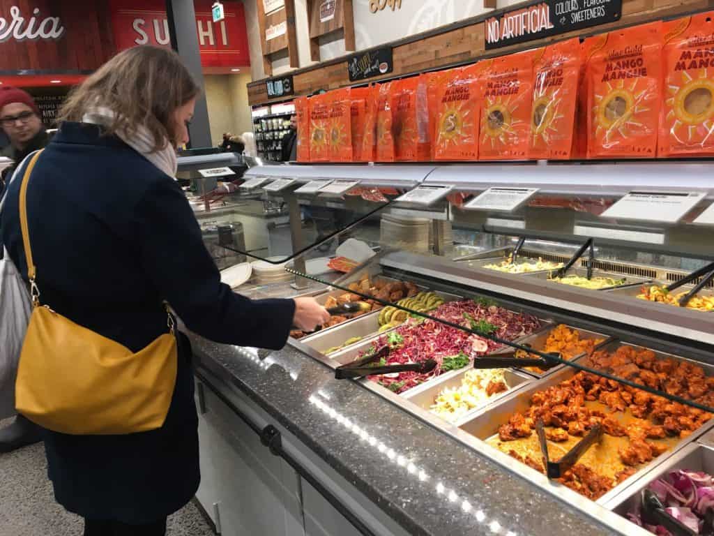 Woman selecting hot food at supermarket