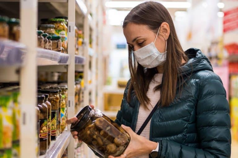 Young woman in medical mask in grocery store because of Covid 19